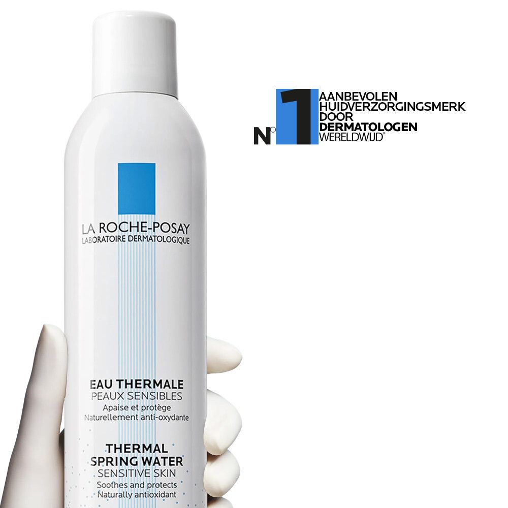 Wit spray, vastgehouden door een hand. Blauw logo. Tekst: La Roche-Posay, Eau Thermale, Thermal Spring Water, Sensitive Skin.
