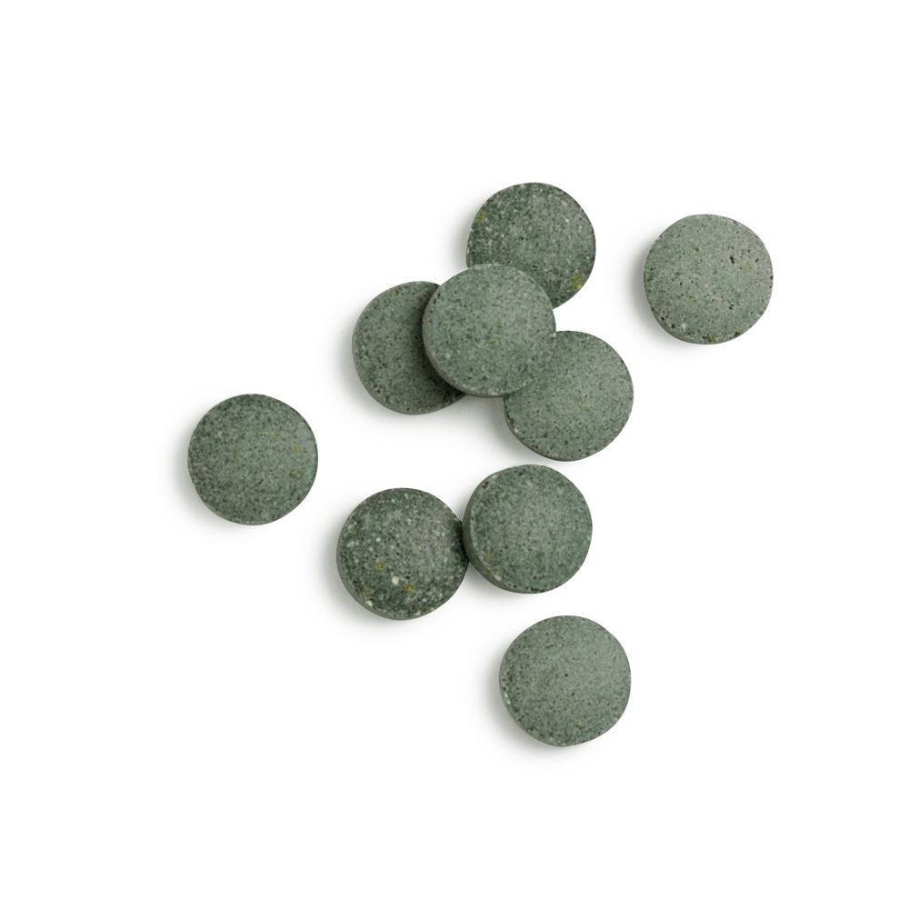Ronde, groene tabletten op witte achtergrond. Meerdere tabletten liggen los.