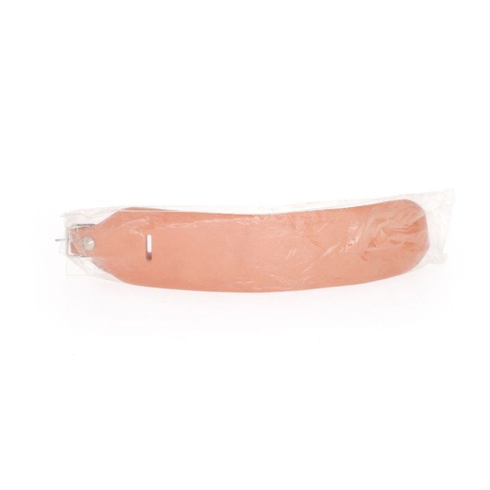 Bracelet de poignet en cuir, emballé. Beige. Fermoir métallique. Visible dans un emballage plastique.