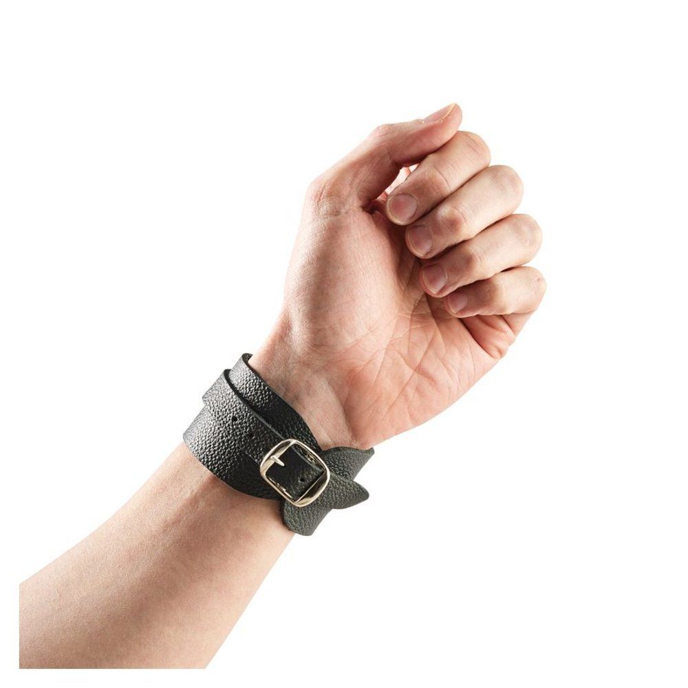 Zwarte leren polsband om een pols. Met metalen gesp. Close-up.