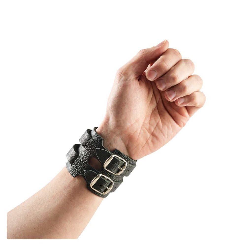 Bracelet de poignet en cuir noir à double largeur avec deux boucles, porté sur un poignet.