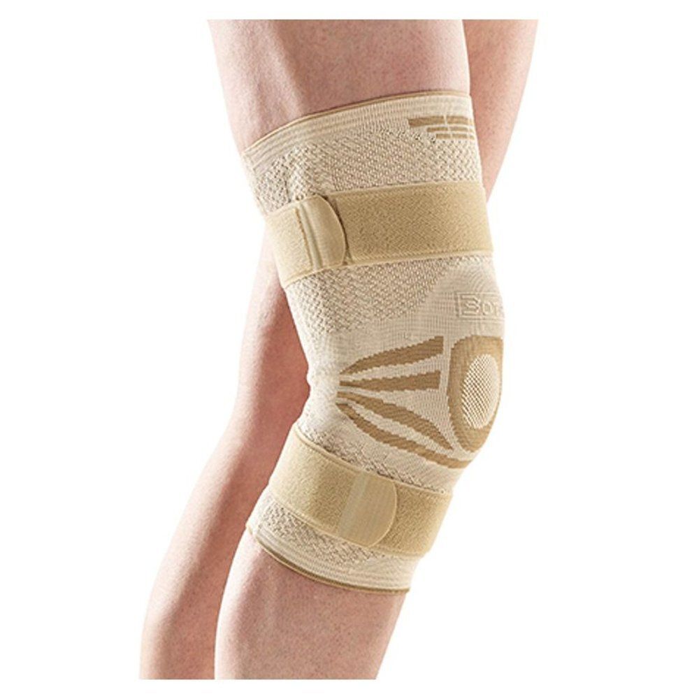 Beige kniebrace met klittenbandsluitingen. Gedragen op de knie, detailweergave.