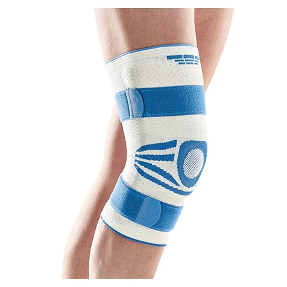 Bota Ortho kniebrace, wit en blauw. Klittenbandsluitingen, gewatteerde zones, gedragen op been.