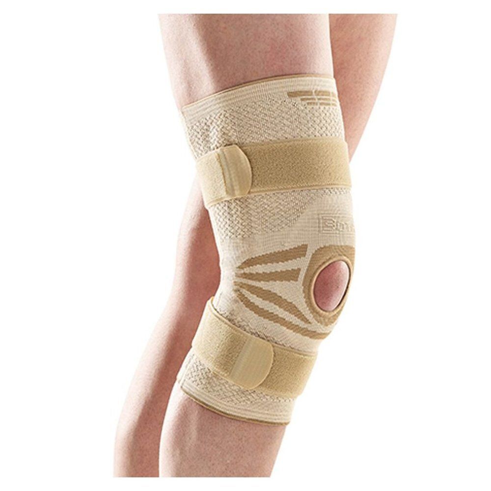 Genouillère beige, avec fermetures velcro et ouverture. Portée sur une jambe.