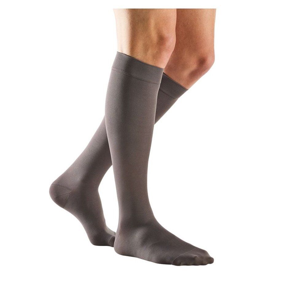 Bas de contention gris. Vue latérale des jambes. Les bas couvrent les pieds et le bas des jambes.
