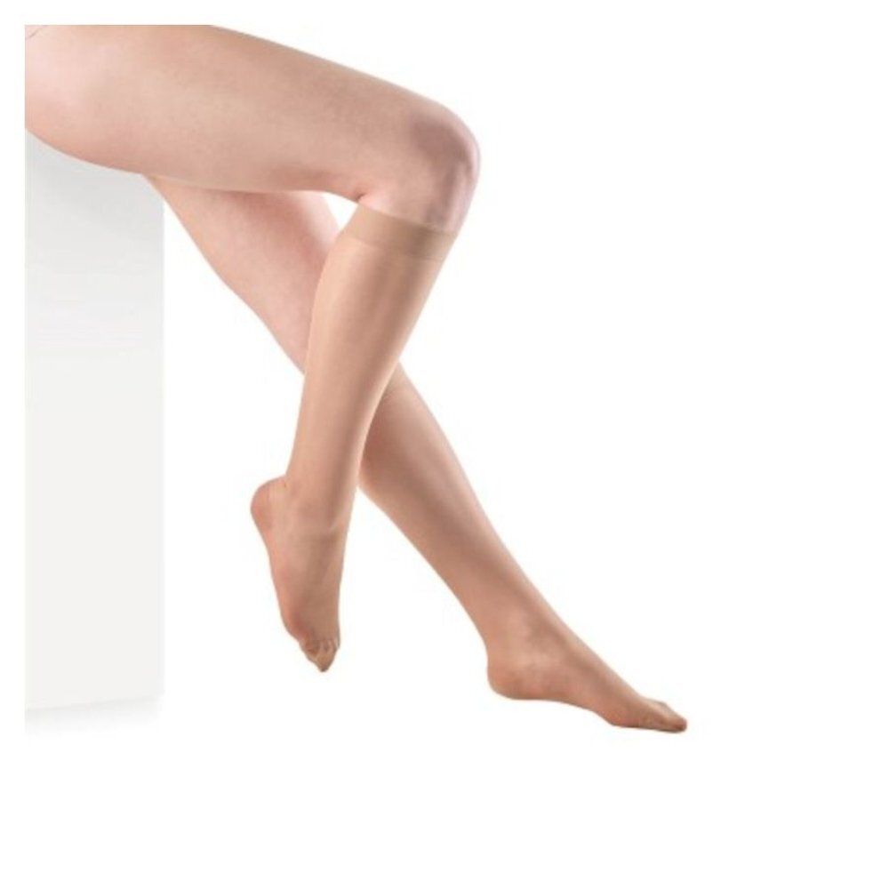 Jambes d'une personne portant des bas genoux. Les bas sont couleur chair et s'arrêtent au genou. Le fond est blanc.