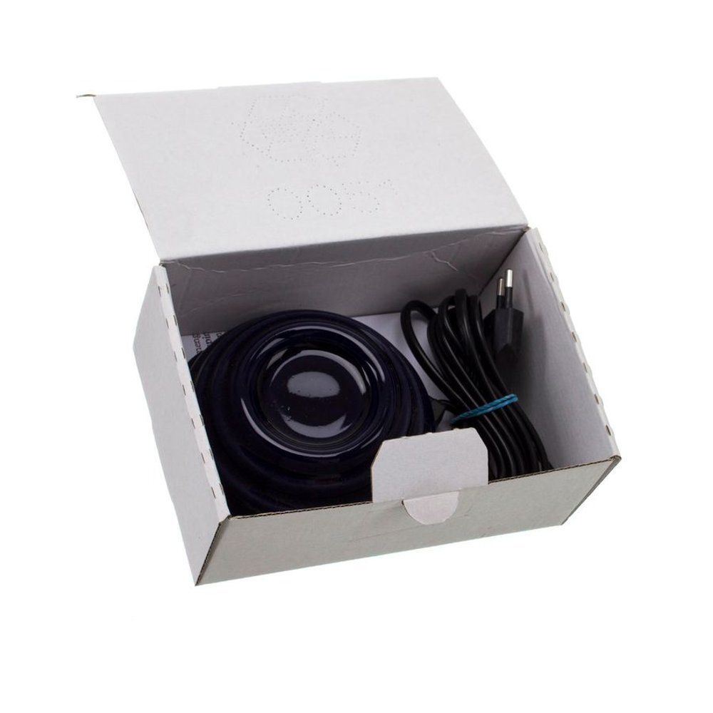 Boîte blanche ouverte contenant un objet rond noir, un câble et une prise. L'objet est placé à l'intérieur de la boîte.