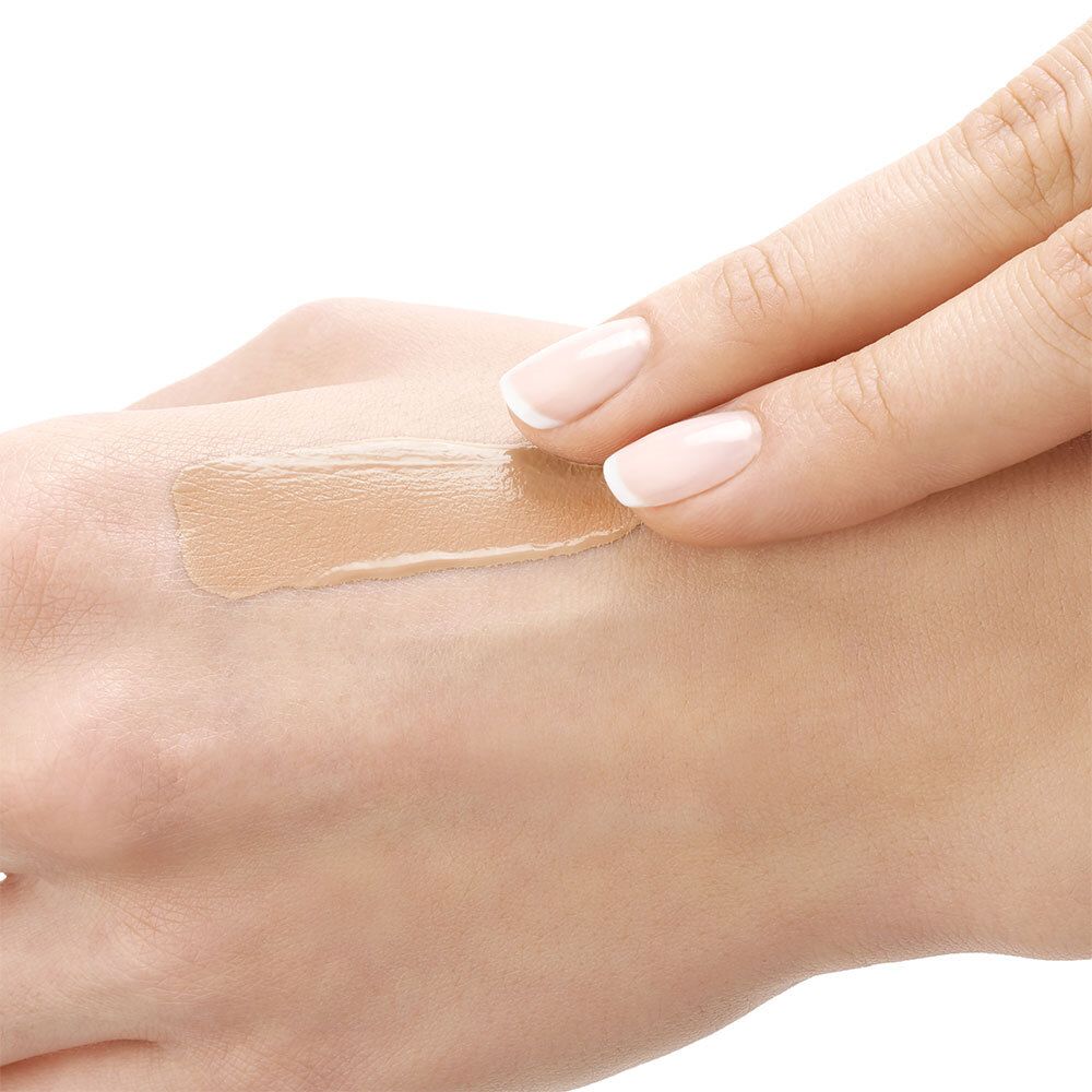 Hand met aangebrachte foundation. Vloeibare foundation uitgesmeerd.