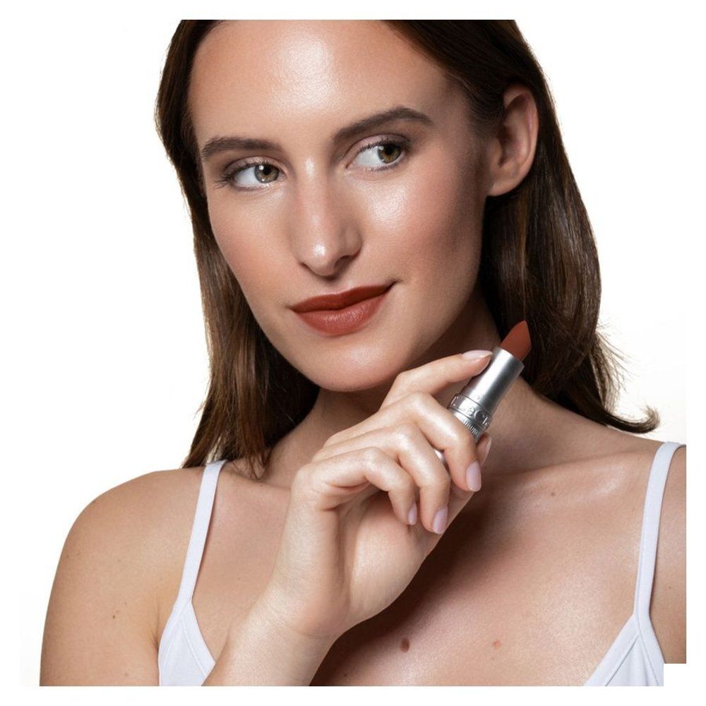 Vrouw houdt lippenstift vast. Lippenstift op lippen. Zilveren huls.