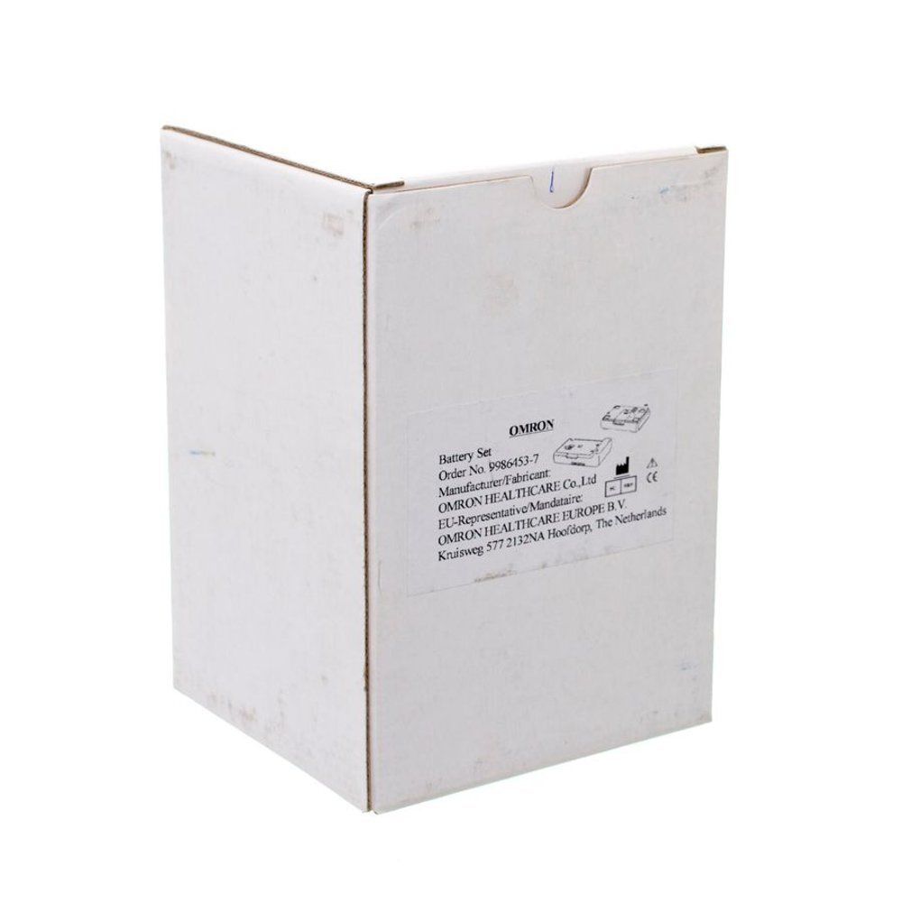 Emballage en carton blanc. Inscriptions: OMRON, Battery Set. Informations fabricant et marquage CE.