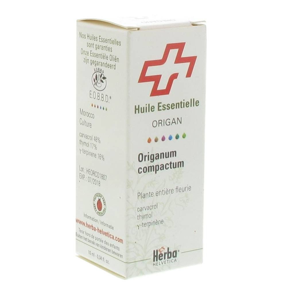 Kartonnen verpakking met rood kruislogo. Tekst: Huile Essentielle Origanum compactum. Herba Helvetica logo.