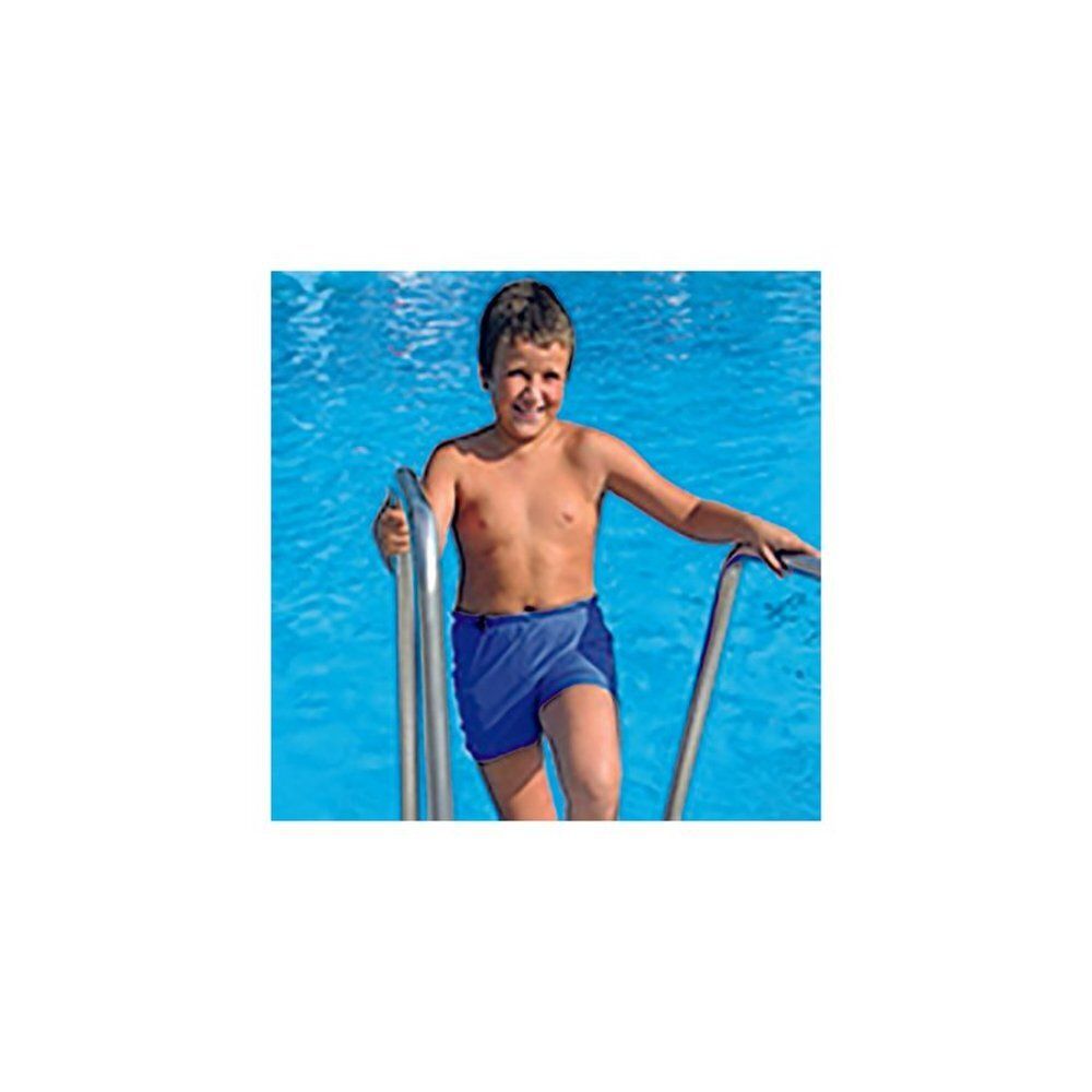 Jongen in blauwe zwembroek die een zwembadtrap gebruikt. Hij staat in het water en glimlacht.