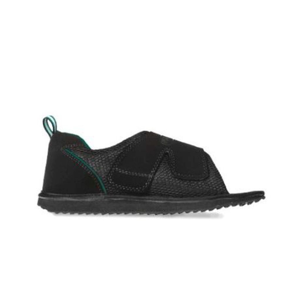 Chaussure noire avec fermeture velcro. Matériau texturé. Accents verdâtres au talon. Vue latérale.