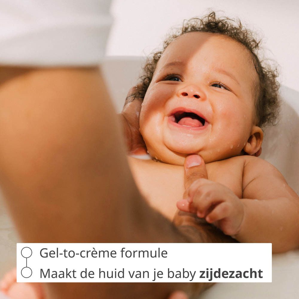 Ouders badderen een baby in een babybadje, met een Weleda Baby Calendula Cremebad fles ernaast.