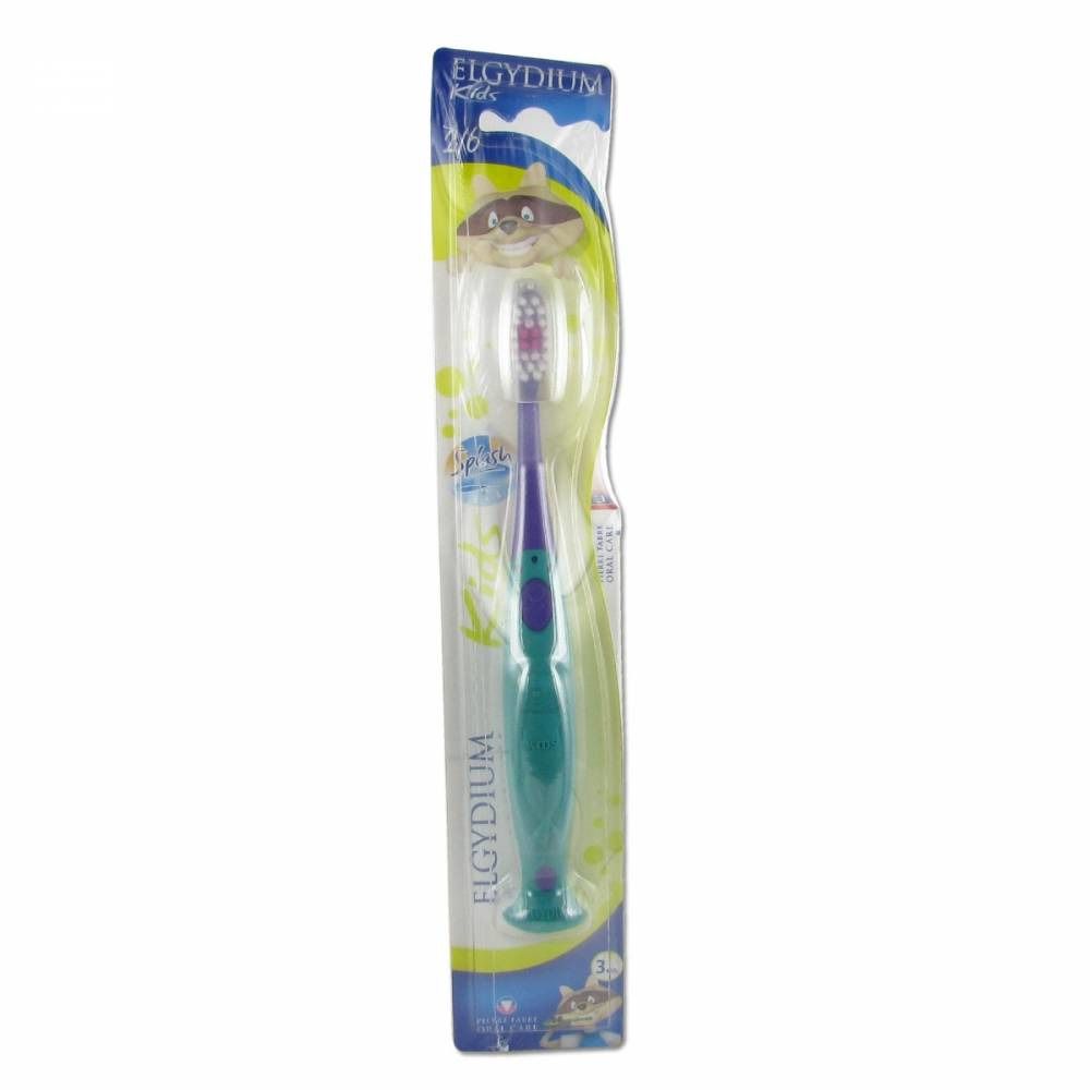 Brosse à dents enfant sous blister. Manche vert, poils violets. Logo "Elgydium Kids". Emballage avec illustration de dessin animé.