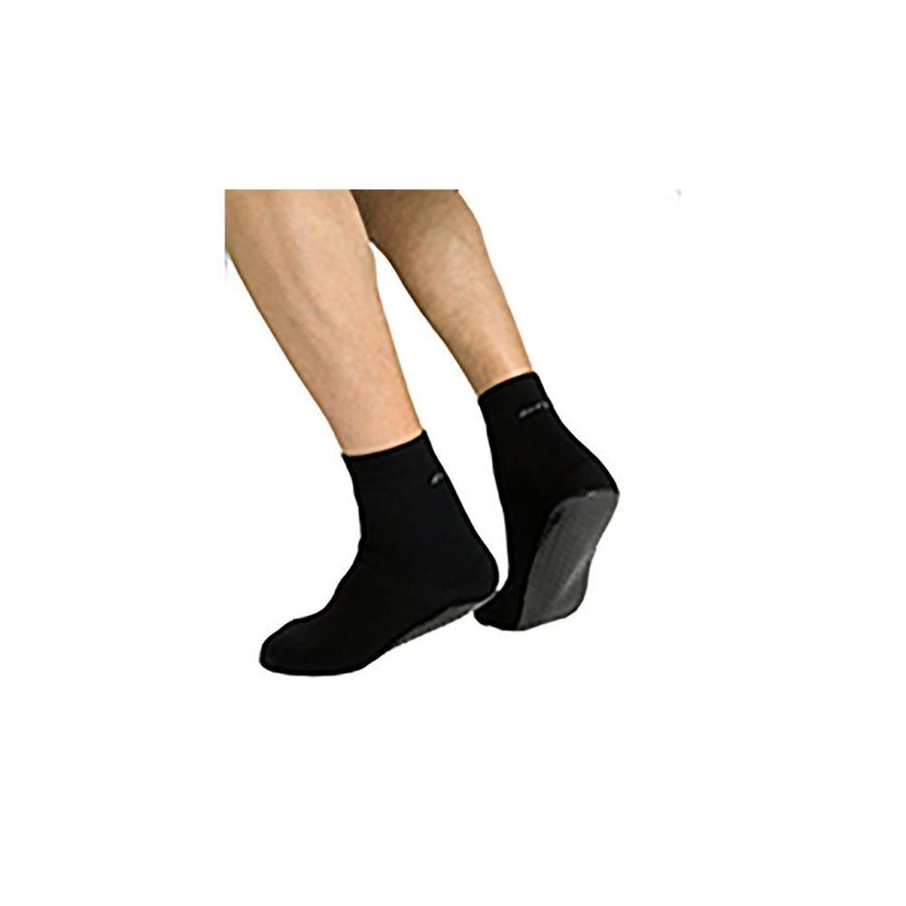 Chaussettes noires avec semelle caoutchoutée. Pieds dans des chaussettes. Semelle caoutchoutée visible. Marque non reconnaissable.