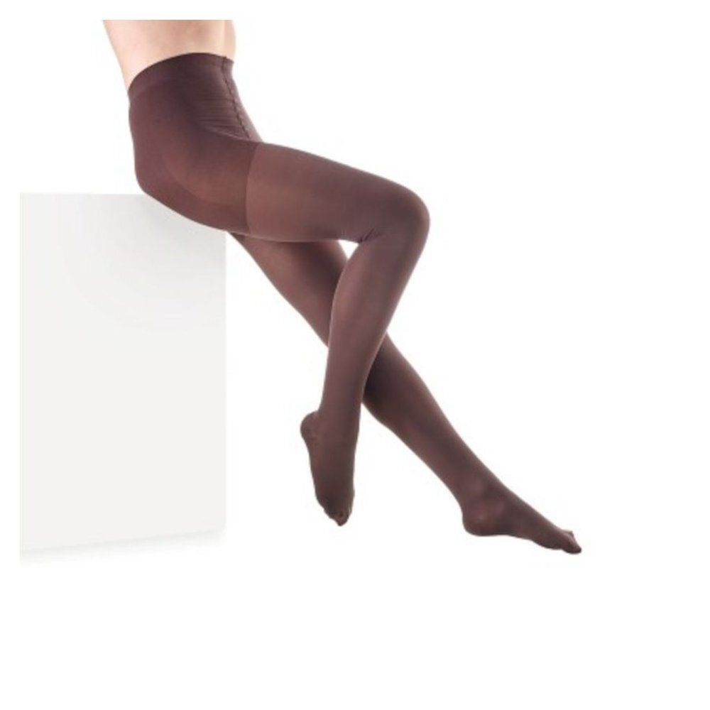 Bruine panty. Persoon zit op wit voetstuk. Beenmode.