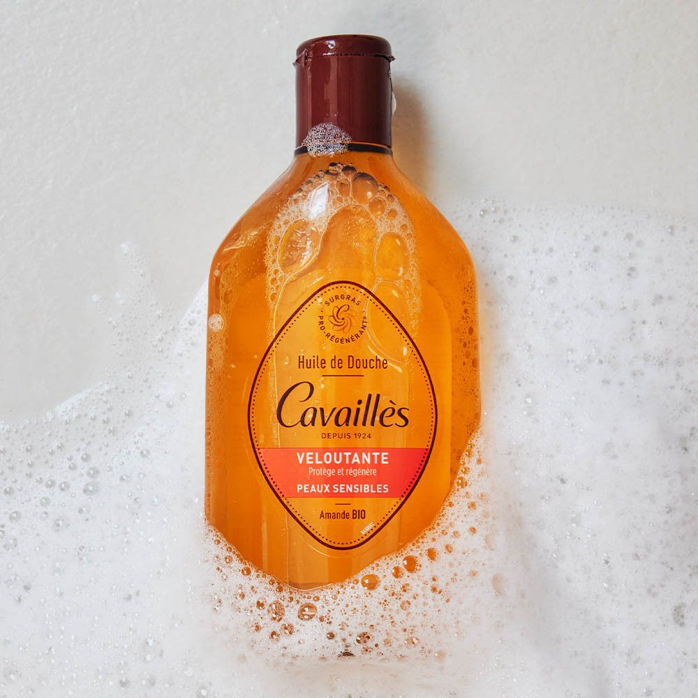 Fles in schuim. Opschrift: Rogé Cavaillès, Huile de Douche Veloutante, Amande Bio. In een schuimbad.