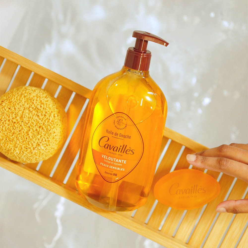 Flacon, savon et éponge sur plateau en bois. Inscription: Rogé Cavaillès, Huile de Douche Veloutante, Peaux Sensibles.
