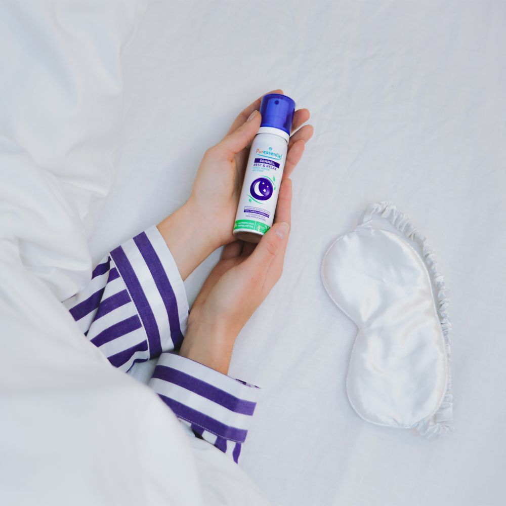Main pulvérisant Puressentiel Spray détente dans une chambre d'enfant.