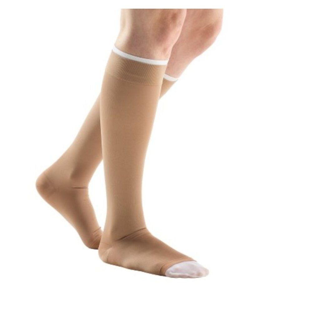 Bas de compression beiges sur une jambe. Finition blanche sur le bord supérieur. Zone des orteils ouverte.
