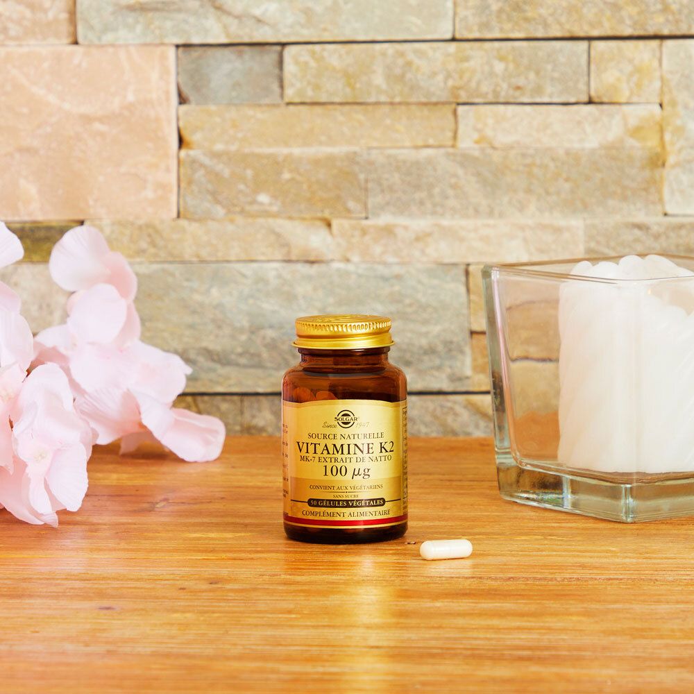 Flacon doré sur bois, une gélule à côté. Fond: mur en pierre.