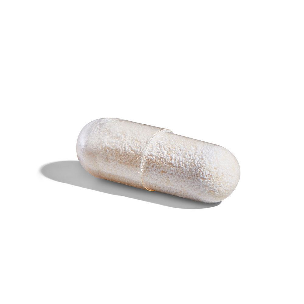 Une gélule oblongue, crème. Sur fond blanc.