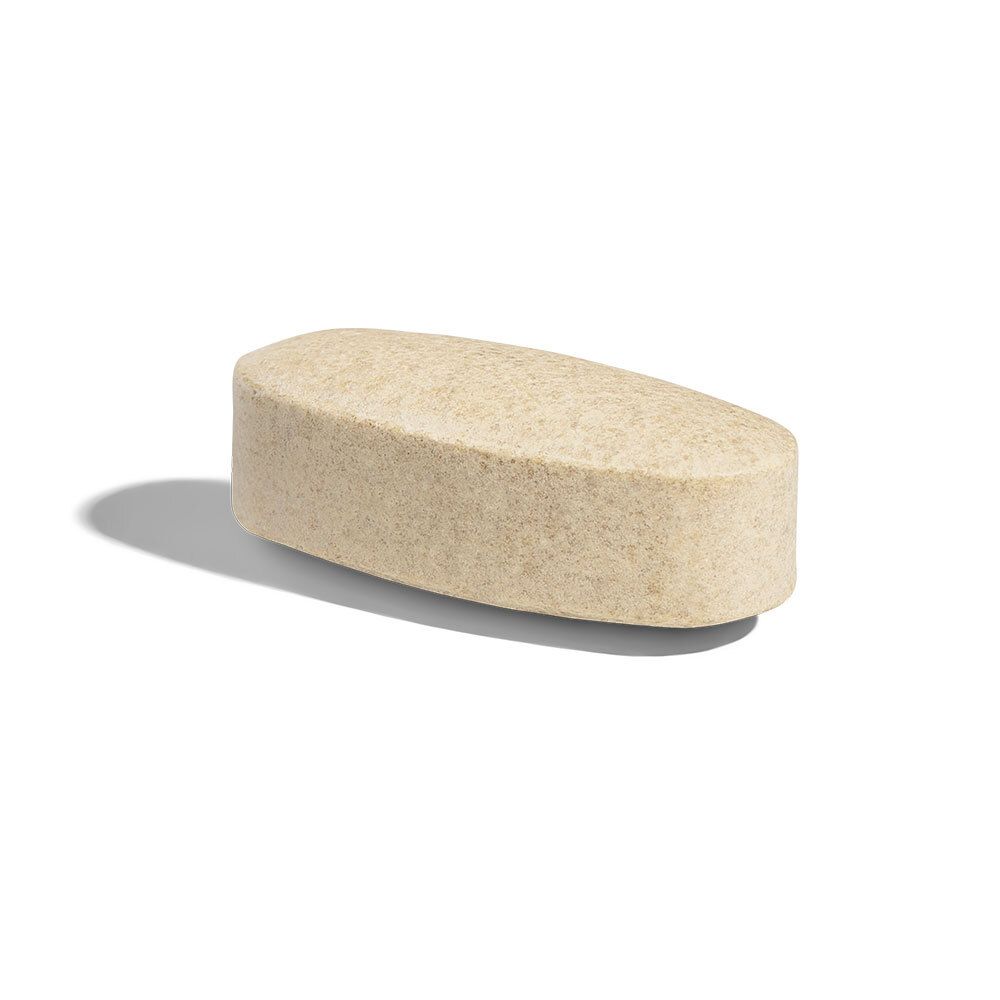 Comprimé unique, oblong. Couleur beige clair. Bords arrondis. Repose sur fond blanc.