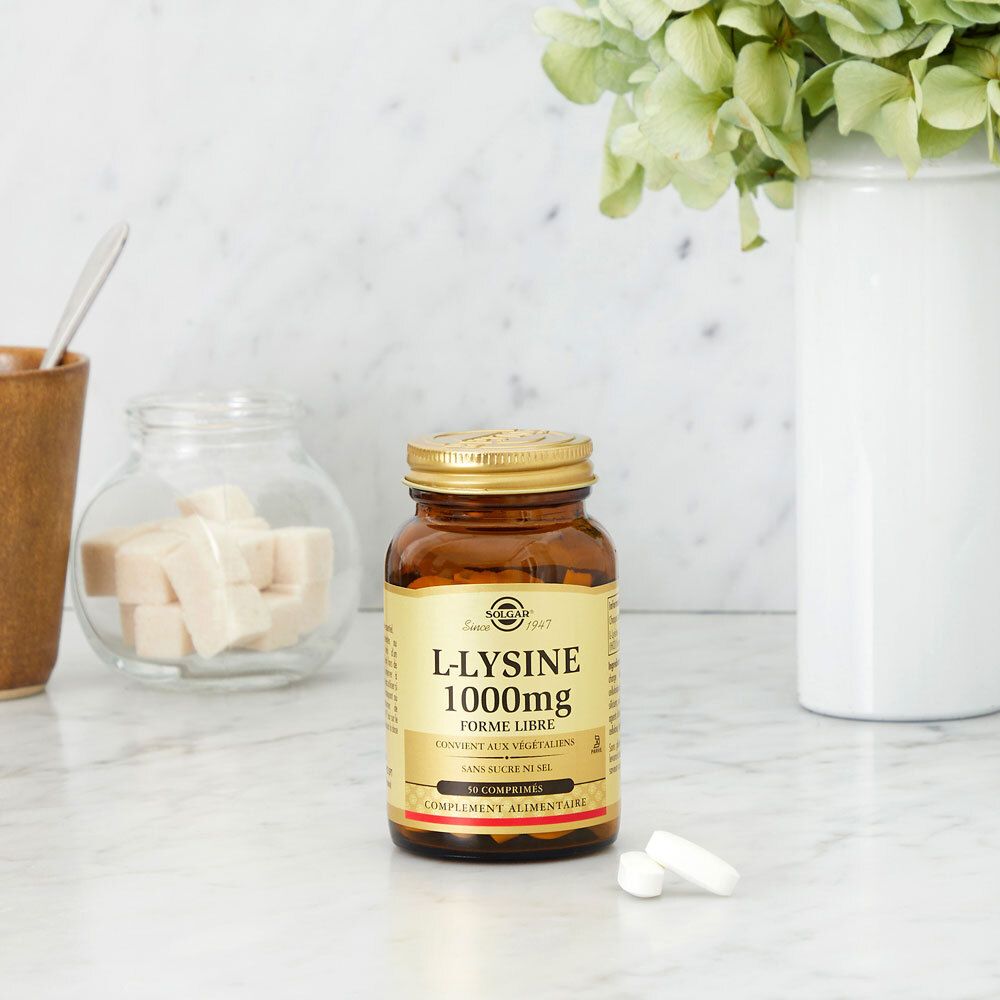 Flacon brun Solgar® L-Lysine 1000 mg sur une surface en marbre, à côté de décorations.