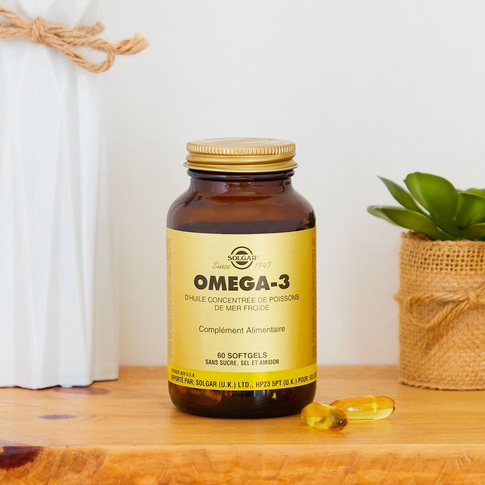 Flacon brun, bouchon doré. Inscription Omega-3. À côté de décorations.