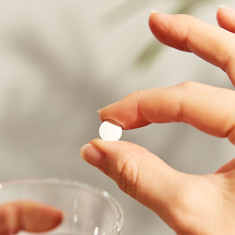 Main tenant un comprimé blanc unique. Gros plan.