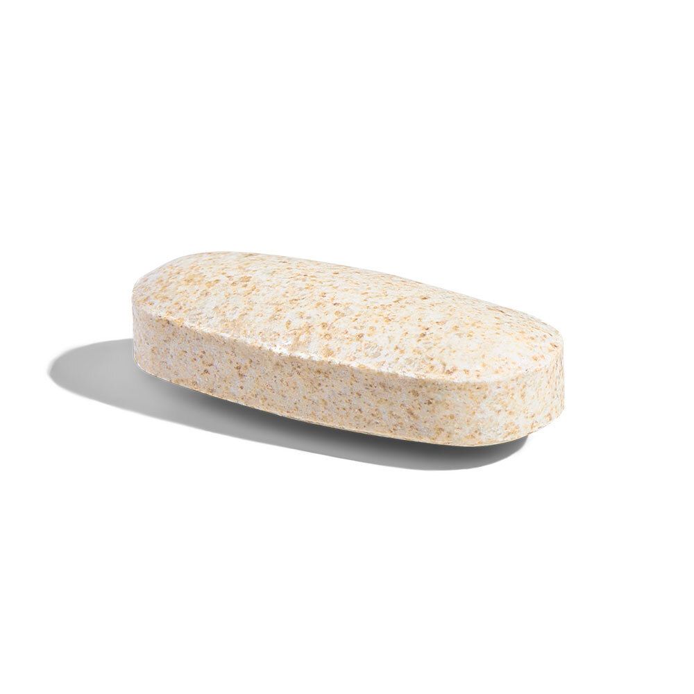 Un seul comprimé oblong. Couleur beige. Posé sur une surface blanche.