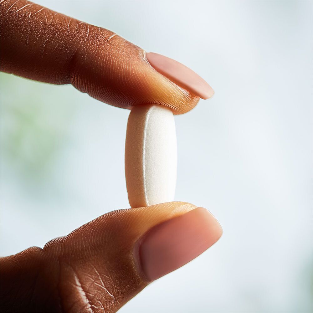 Hand houdt witte, ovale tablet vast. Roze nagels. Close-up.