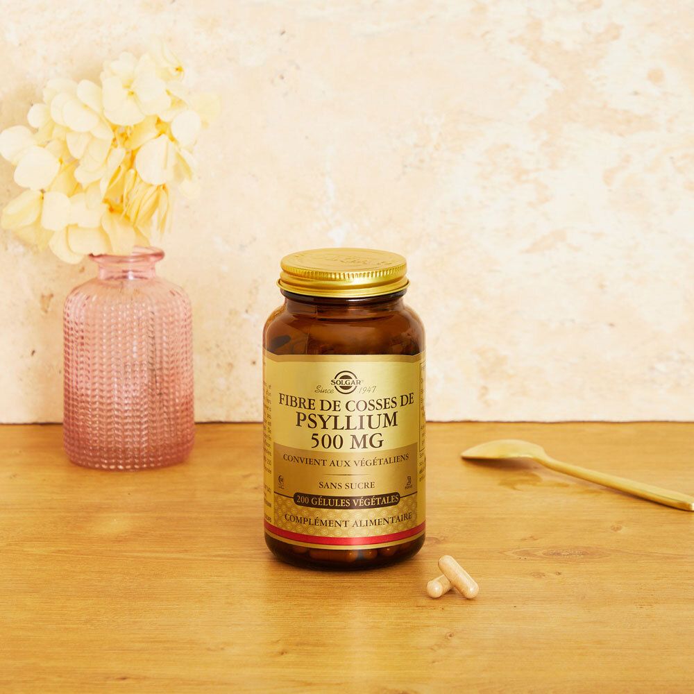 Bruine fles met capsules en lepel op houten oppervlak. Achtergrond: vaas met bloemen.