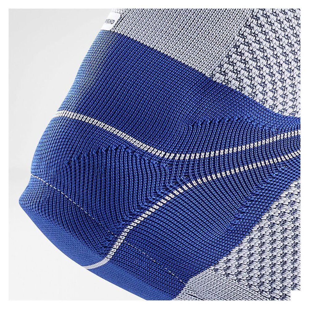 Close-up van enkelbrace. Blauwe band met witte strepen. Grijs, gestructureerd textiel.