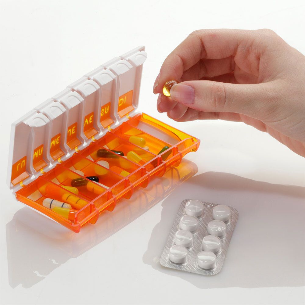Open pillendoos met medicijnen, een hand pakt een pil.