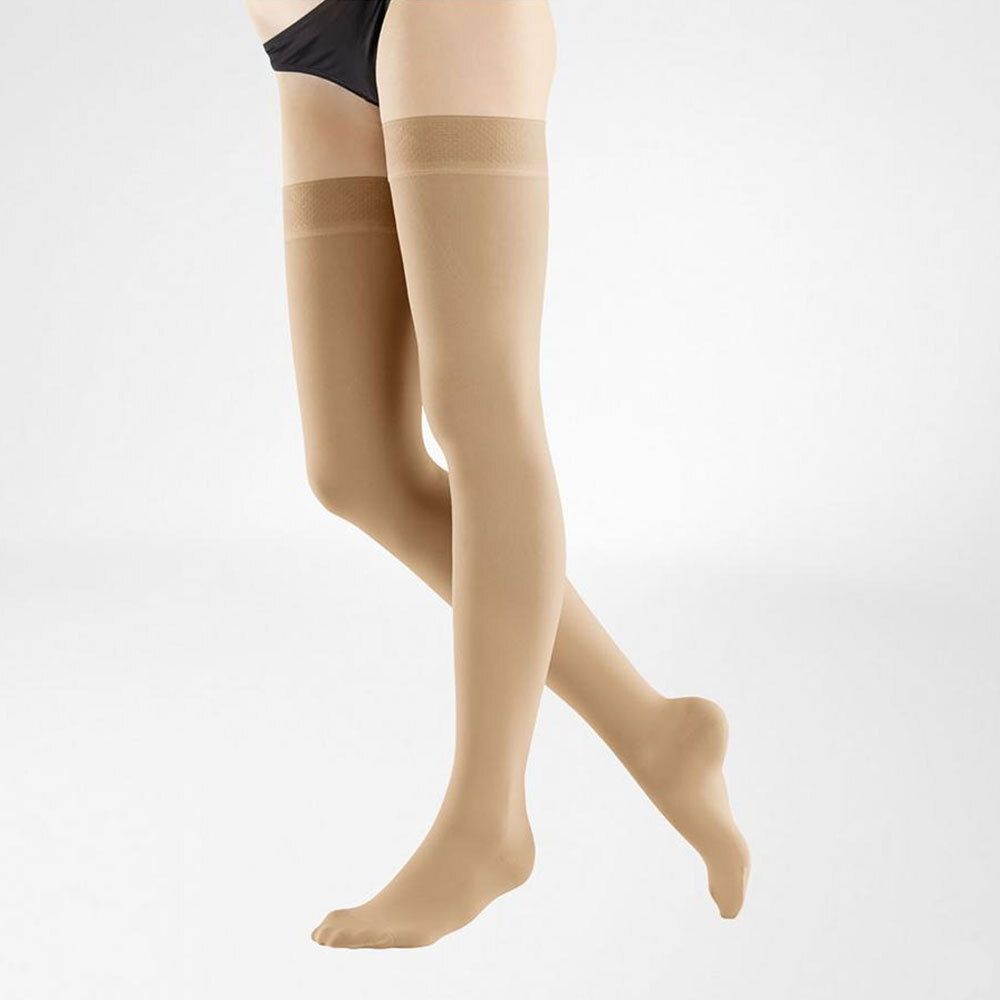 Bas de compression beiges, hauteur genou. Conception sans couture. Sur fond clair, vue de côté.