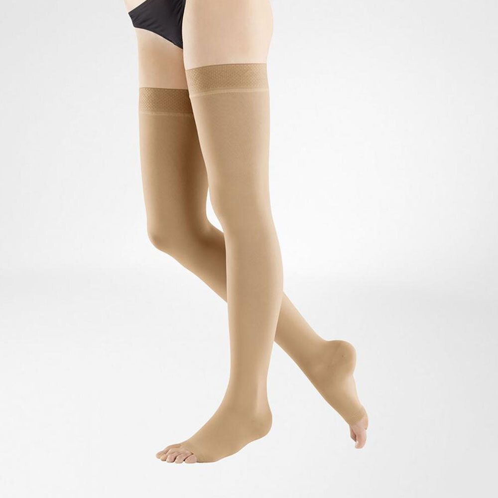 Bas de compression beiges, montants aux genoux, bout ouvert. Portés par une personne, sur fond clair.