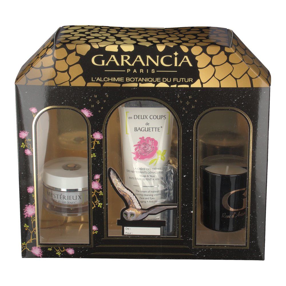 Coffret cadeau noir et or avec trois produits visibles : crème, tube et bougie. Fenêtres en façade.