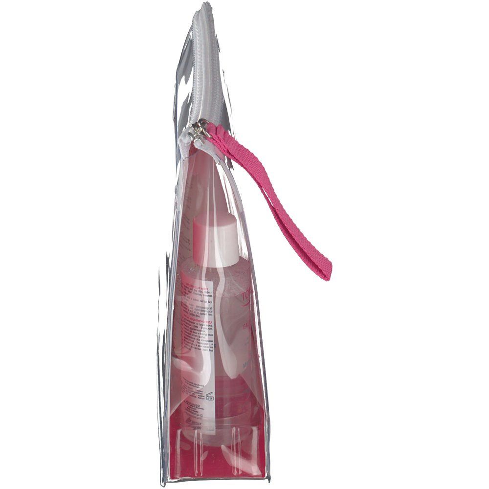 Vue latérale de la trousse de voyage transparente Topicrem. Boucle de préhension rose. Produits visibles à l'intérieur.