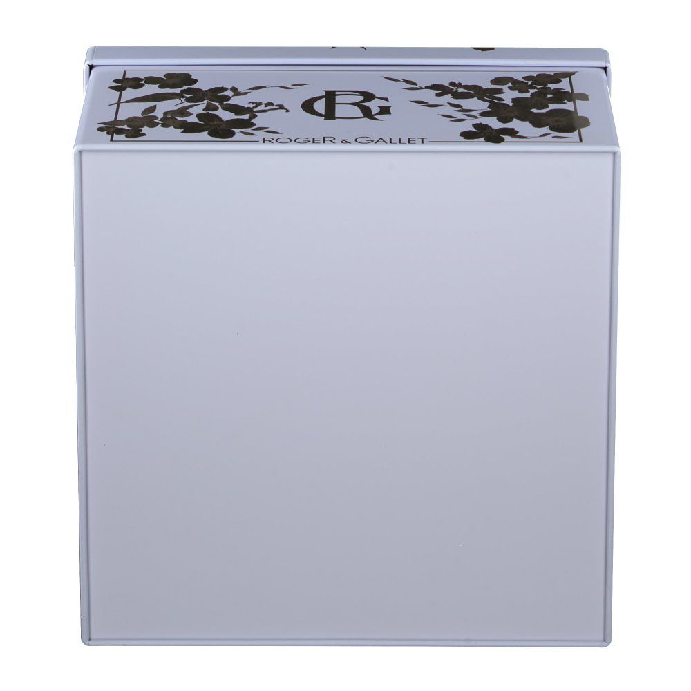 Boîte blanche avec motifs floraux dorés et nom de la marque. La boîte est carrée et a un couvercle.