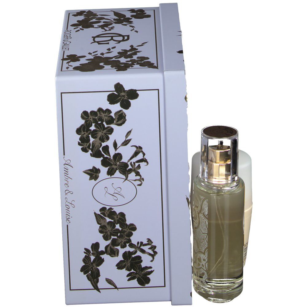 Coffret cadeau avec flacon et déodorant à côté d'une boîte blanche. La boîte a des motifs floraux dorés et le nom de la marque.