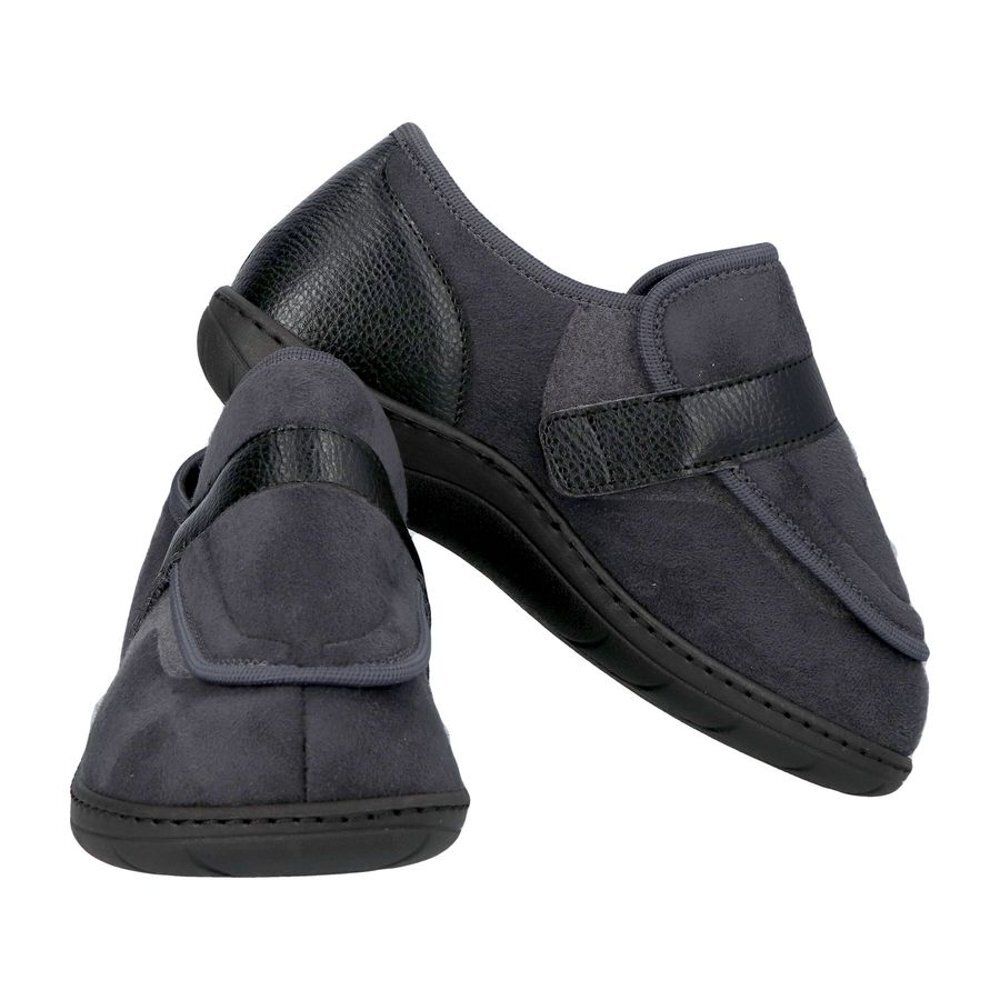 Chaussures de confort grises. Bride velcro. Semelle et talon noirs. Deux chaussures, une légèrement surélevée.