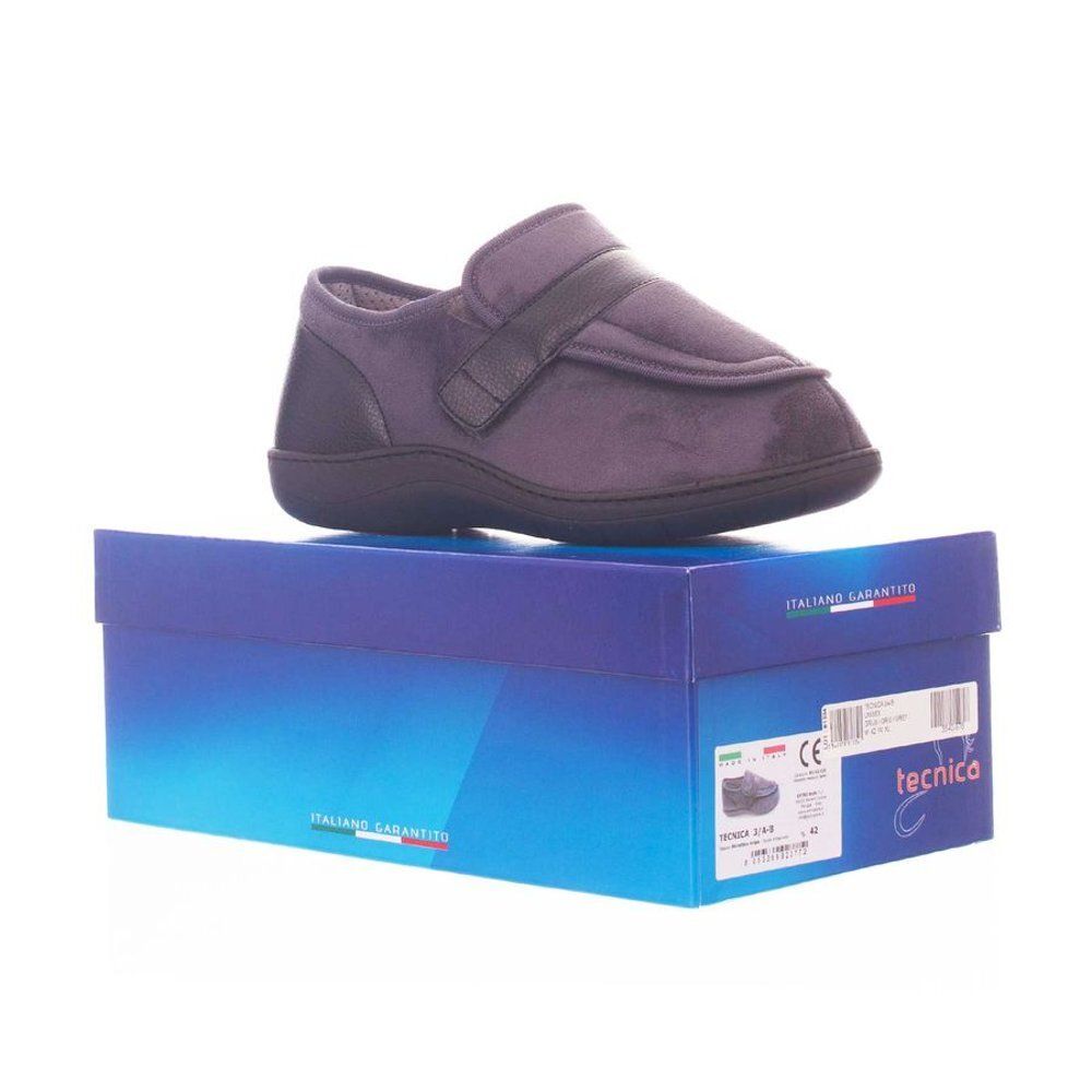 Grijze schoen met klittenbandsluiting op een blauwe doos. Zwarte zool en hiel. Model: Bota Tecnica 3A-B Comfort.