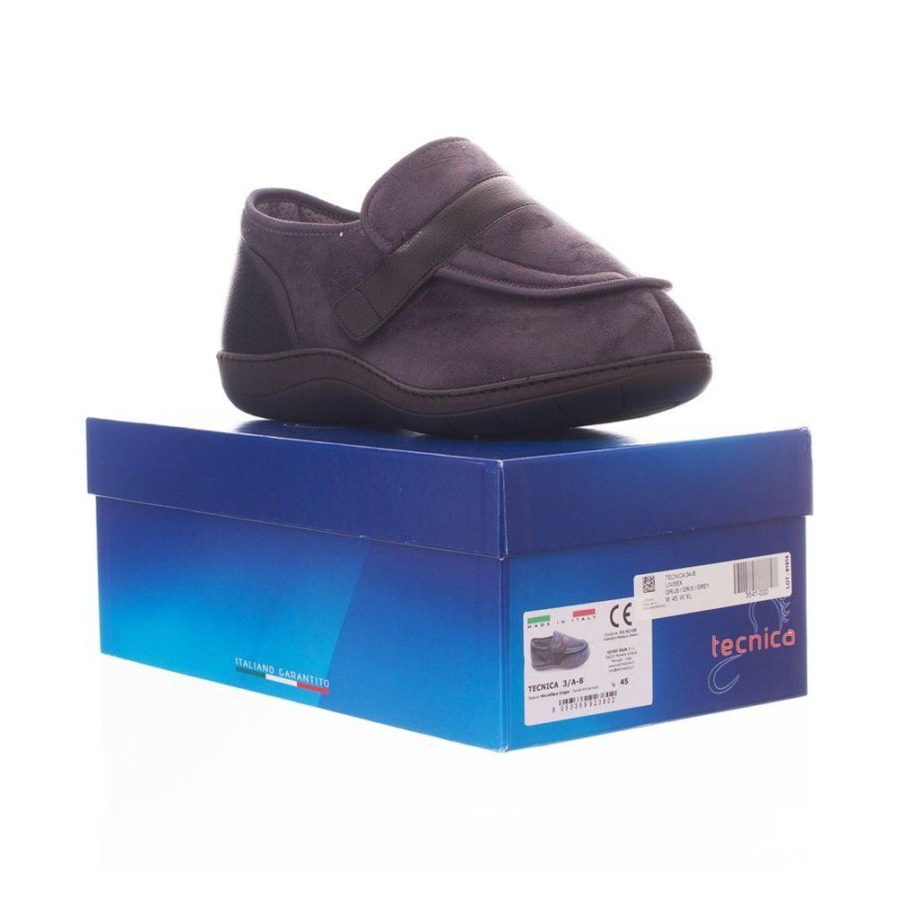 Slipper gris confort sur boîte bleue. Semelle et talon noirs. Fermeture velcro. Emballage du produit.