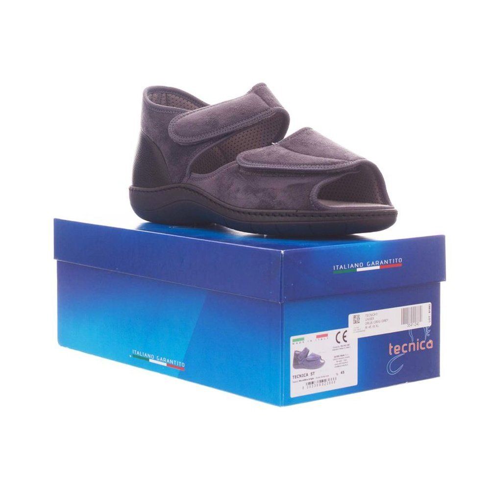 Grijze schoen op blauwe doos. Klittenbandsluitingen, open teen. 'tecnica' staat op de doos.