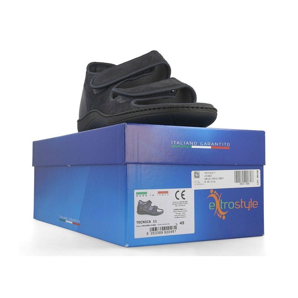 Chaussure noire sur boîte bleue. Fermetures velcro. Étiquette avec informations produit.