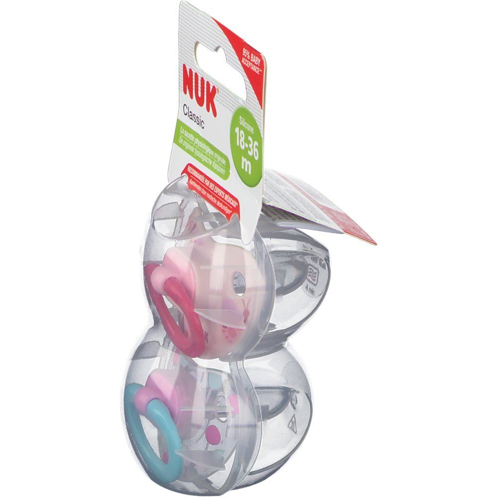 Deux sucettes NUK Classic en silicone, 18-36 mois. Vue latérale. Anneaux rose et bleu.