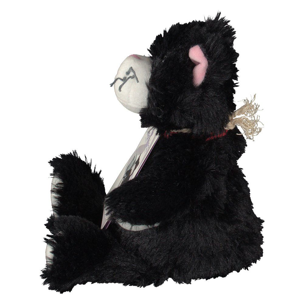 Chat noir en peluche de profil, assis. Visible : visage blanc, oreille rose, étiquette. Étiquette avec image du produit.