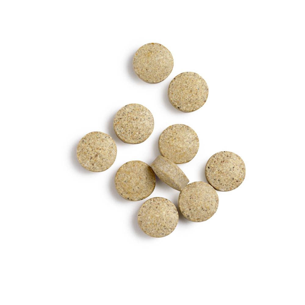 Ronde, beige tabletten op witte achtergrond. Enkele tabletten liggen verspreid. Geen verpakking zichtbaar.